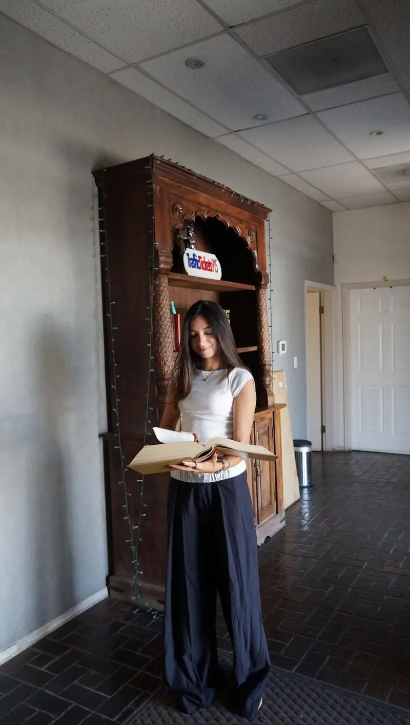 Traffic Tickets 915 team member reading an open law book beside a wooden bookcase in the El Paso office