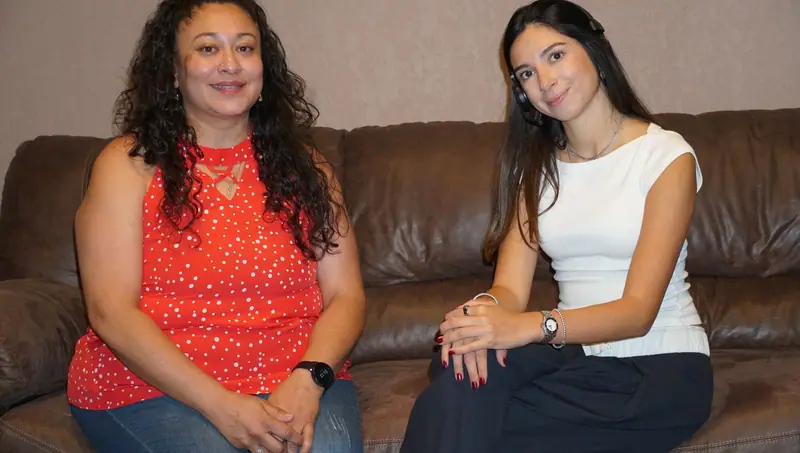 Two Traffic Tickets 915 team members seated on a brown leather sofa in the El Paso office, one wearing a headset